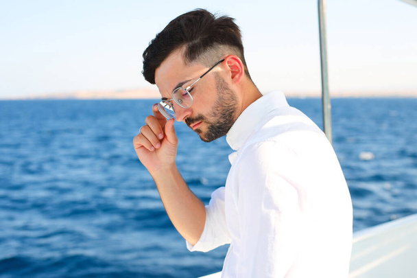 Un ritratto di un uomo d'affari serio con gli occhiali, tenetegli la mano per loro. In barca in mare - Foto, immagini