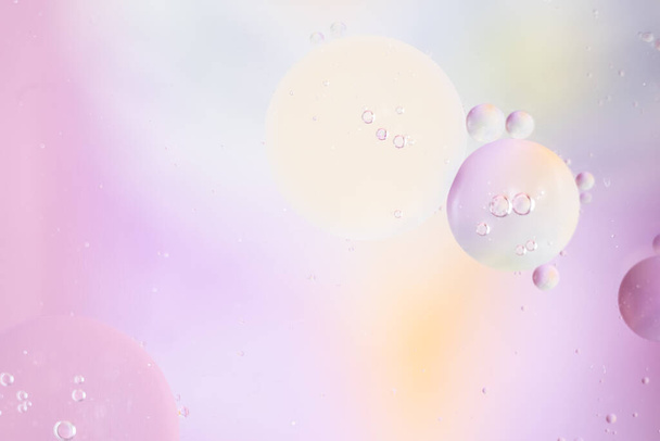 Abstract background in pale pink colors. Macro drops of oil on the surface of the water. Delicate cosmetic bubbles background for promotional products. copy space and gradient.  - 写真・画像
