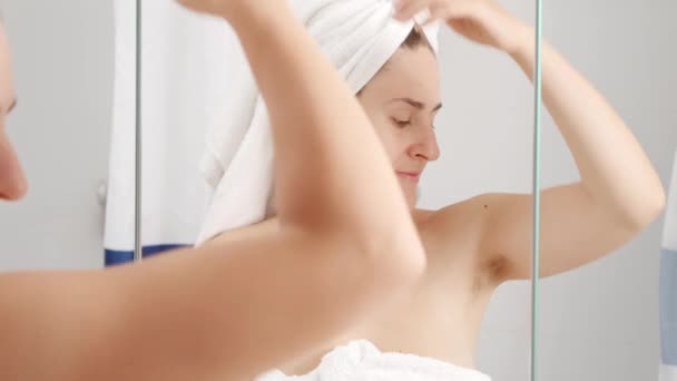 Nuori nainen suihkun jälkeen tunne paha haju ja soveltamalla deodorantti. Käsitys hygieniasta, luonnon kauneudesta, naisellisuudesta ja kehon hiusten kasvusta - Materiaali, video