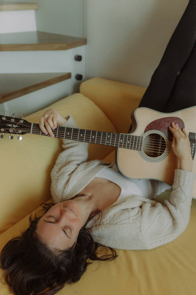 Creative hobby. Talented young female musician sit in armchair alone compose instrumental song using classic guitar. Smiling lady play calm melody on musical instrument. Copy space - Foto, Imagen
