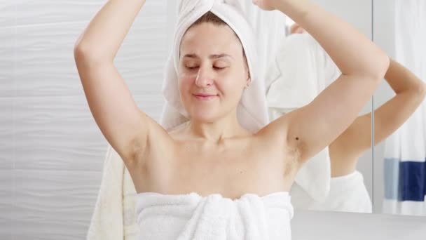 Retrato de mujer sonriente con el pelo largo creciendo bajo los brazos de pie en el baño después de la ducha. Concepto de higiene, belleza natural, feminidad y crecimiento del vello corporal - Metraje, vídeo