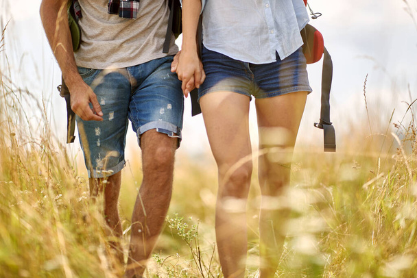 Close up shot of couple hiking in field,  holding hands. Nature outdoors. Caucasian couple. Sport, freedom, holiday concept. - Photo, Image