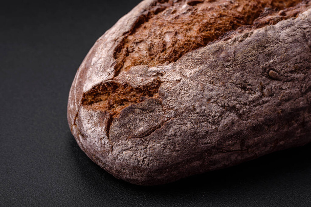 Delicious fresh brown sourdough bread with grains on dark concrete background - Foto, Imagem