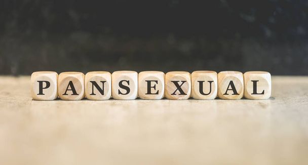 Inscription Pansexual written on wooden cubes. Black background.  - Foto, afbeelding