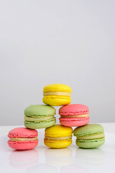 The girl flicks the macaroon with her finger to the side. Macaroon rolls to the side. Art. Natural ingredients. Multi-colored macaroons. Food concept. High quality Colorful tasty macaroons rotating - Fotó, kép