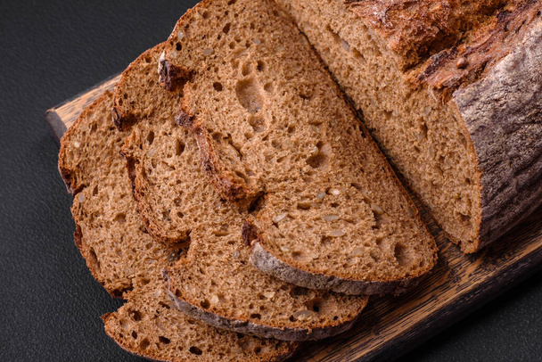 Lahodný čerstvě hnědý kysaný chléb se zrny na tmavém betonovém pozadí - Fotografie, Obrázek