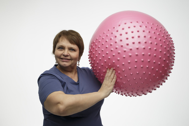 reife Frau macht Übungen mit rosa Ball im Studio - Foto, Bild