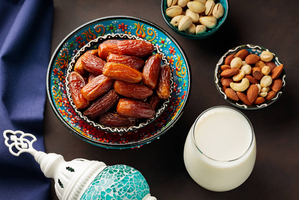 Dried dates, nuts and milk on a dark background. Ramadan Kareem and iftar muslim food and Turkish lamp. Ramadan concept. Top view - Foto, Bild