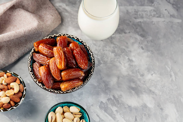 Ramadan Kareem Essen und Trinken. Getrocknete Datteln, Nüsse und Milch auf grauem Hintergrund. Islamische Religion und Ramadan-Konzept. Ansicht von oben. Kopierraum - Foto, Bild