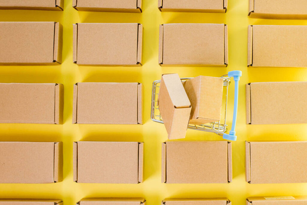 Shopping cart with boxes on a yellow background. The concept of sales, discounts, online shopping and delivery - Fotó, kép