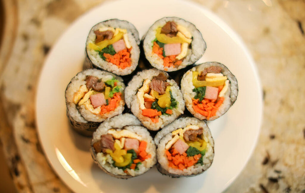 sushi rolls with salmon, avocado, cucumber and sesame seeds on a plate - 写真・画像