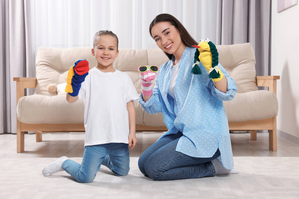 Happy mother and daughter playing with funny sock puppets together at home - Fotó, kép