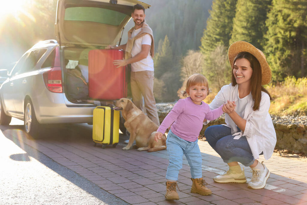 Mother with her daughter, man and dog near car outdoors. Family traveling with pet - Foto, immagini