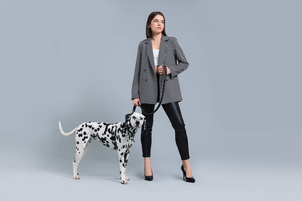 Beautiful young woman with her adorable Dalmatian dog on light grey background. Lovely pet - Photo, Image