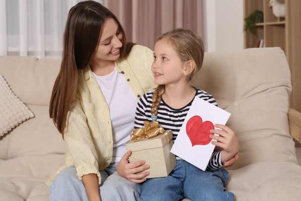 Young woman and her daughter with gifts on sofa at home - Fotografie, Obrázek