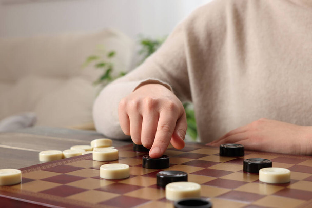 Playing checkers. Woman thinking about next move at table in room, closeup - Foto, immagini