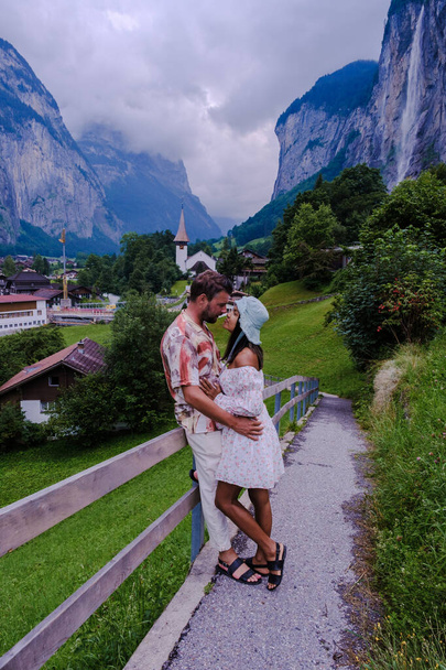 mężczyźni i kobiety odwiedzający dolinę Lauterbrunnen ze wspaniałym wodospadem i Alpami Szwajcarskimi w tle, Berner Oberland, Szwajcaria, Europa latem - Zdjęcie, obraz