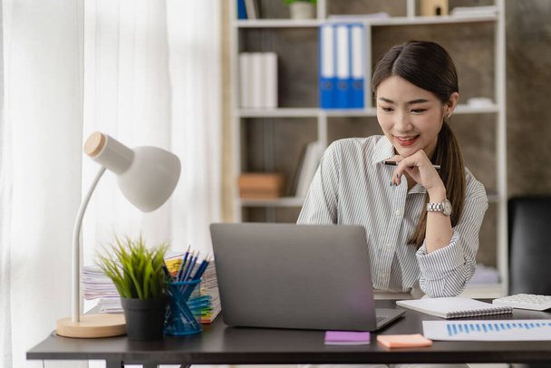 Азиатская деловая женщина сидит за столом в гостиной Работа из дома с помощью ноутбука для онлайн-встречи, финансовая концепция бизнеса. - Фото, изображение