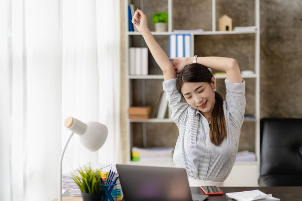 Asian businesswoman relaxing and happy at desk and stretching arms after work done. Relax, chill, take a break during work break. - Foto, Imagem
