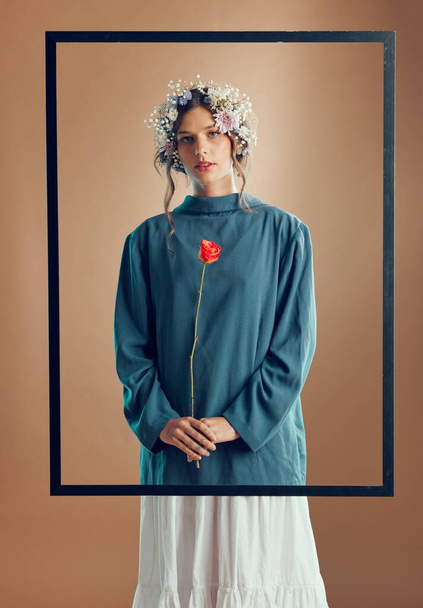 Woman, floral crown and studio with frame, rose or beauty for fashion in portrait by background. Model, girl and flowers in spring, clothes or design with red rose plant in hands by studio background. - Φωτογραφία, εικόνα