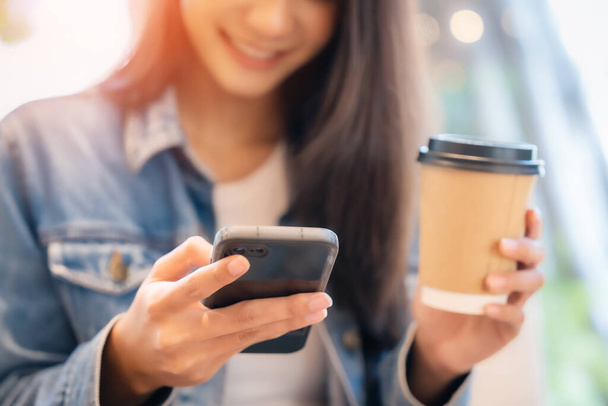 Fiatal ázsiai gyönyörű nő használ okostelefon kávézó kávézó, gépelés üzenet a mobil, online vásárlás, transzfer fizetés, internetes banki - Fotó, kép