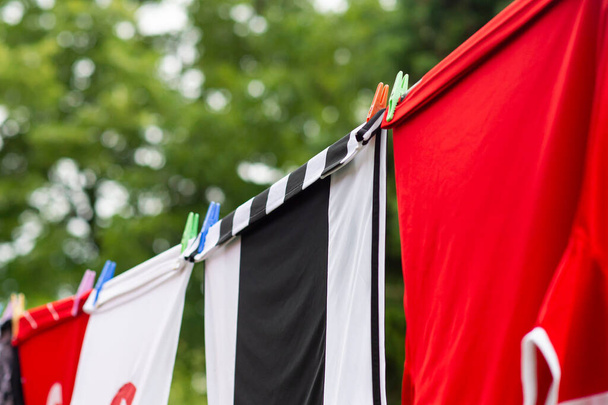 Bunte Kleider hängen zum Trocknen an einer Wäscheleine. Fußballtrikots - Foto, Bild