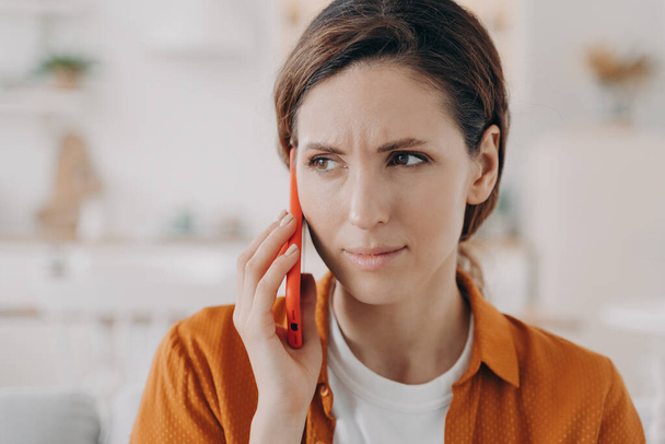 Worried woman or wife has call. Young pretty woman is holding phone at and has talk at home. European girl in casual wear is anxious. Relationships and connections concept. - Fotoğraf, Görsel