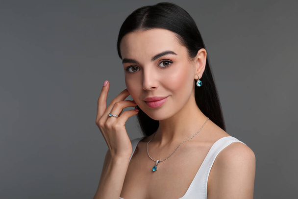Beautiful young woman with elegant jewelry on dark grey background - Fotó, kép
