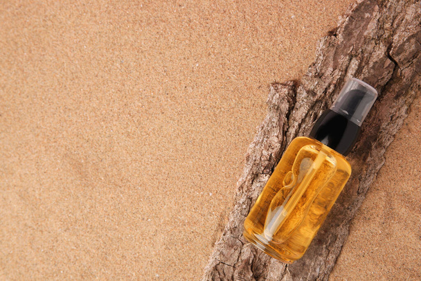 Bottle of serum and tree bark on sand, top view. Space for text - Foto, Imagem