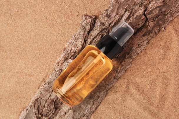 Bottle of serum and tree bark on sand, top view - Foto, Imagem