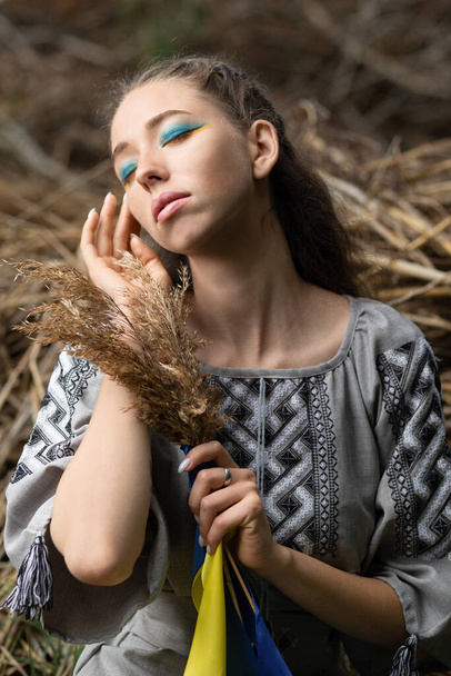 Mavi ve sarı kurdeleli genç bir kızın buğday kulağı vardır. Ukrayna dünyayı tahılla besler. Ukrayna 'da savaş. Ukrayna 'nın acısı. Ukrayna halkının sembolü.. - Fotoğraf, Görsel