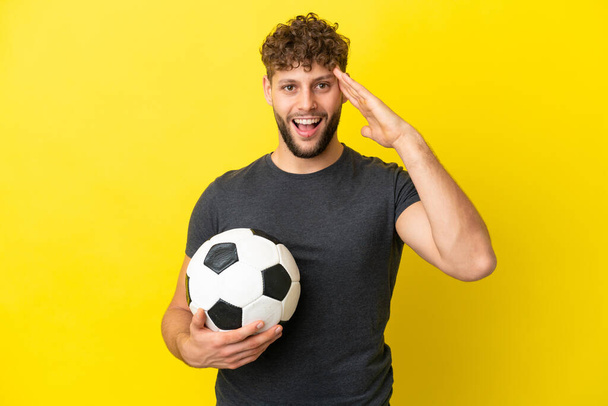 Komea nuori jalkapalloilija mies eristetty keltaisella taustalla yllätyksellä ilme - Valokuva, kuva