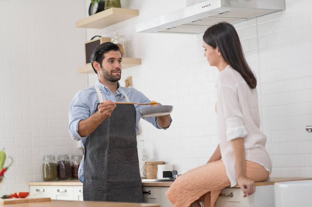 Glückliches junges Paar kocht zu Hause gemeinsam in der Küchentheke - Foto, Bild