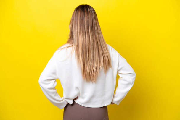 Young Uruguayan woman isolated on yellow background in back position - Foto, Imagem