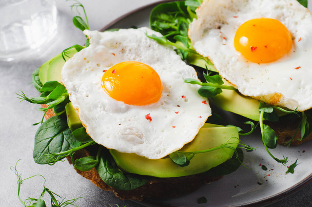 Sandwich all'avocado con uova fritte, colazione sana o spuntino su sfondo luminoso - Foto, immagini