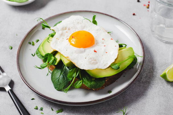 Avocado-Sandwich mit gebratenem Ei, gesundes Frühstück oder Snack auf hellem Hintergrund - Foto, Bild