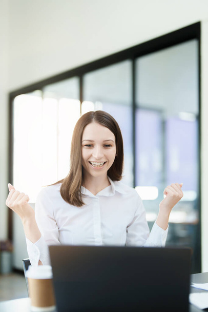 Возбужденная деловая женщина, использующая ноутбук в офисе, бизнес-концепции - Фото, изображение