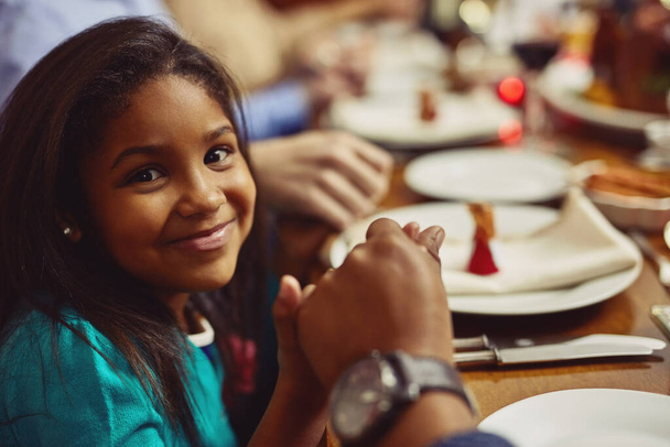 Duayı onun için anlamlı bir uygulamaya dönüştürmek. Birlikte yemek yemeden önce ailesiyle el ele dua eden sevimli küçük bir kızın portresi. - Fotoğraf, Görsel