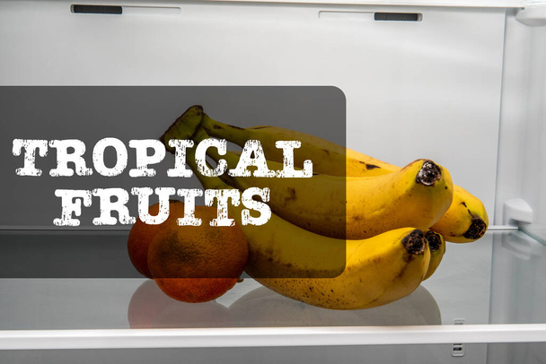 Tropische Früchte. Bananen und Orangen im Kühlschrank. - Foto, Bild