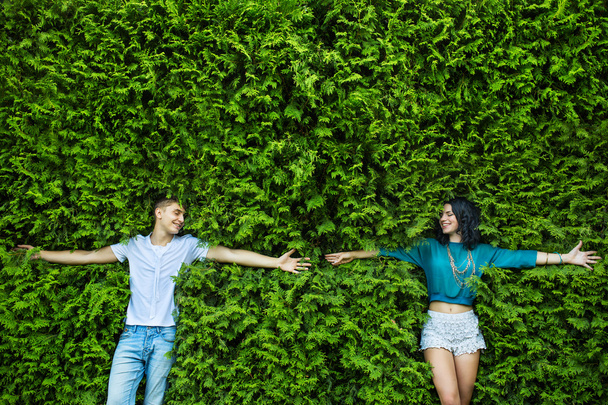 Young couple is closing his eyes back on the bright green foliag - Photo, Image