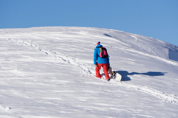 Snowboarder climbing a snowy mountain - Photo, Image