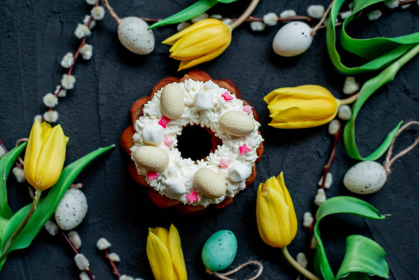 Easter cake, decorative eggs, willow twigs and yellow tulips on a dark background - Foto, imagen