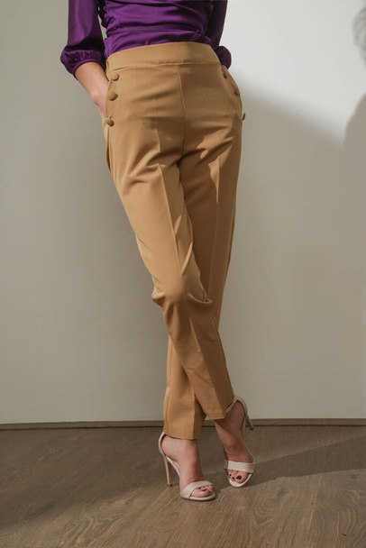 Kobieta modelka ubrana w beżowe, eleganckie spodnie typu high-rise. Zdjęcia studyjne. - Zdjęcie, obraz