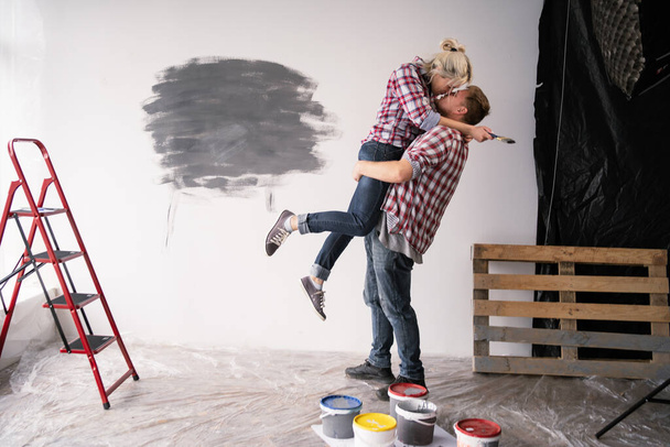 Happy couple repairing, renovation update improvement of the room kissing hugging relaxing preparing to move to a new house apartment. Copy space - Photo, image