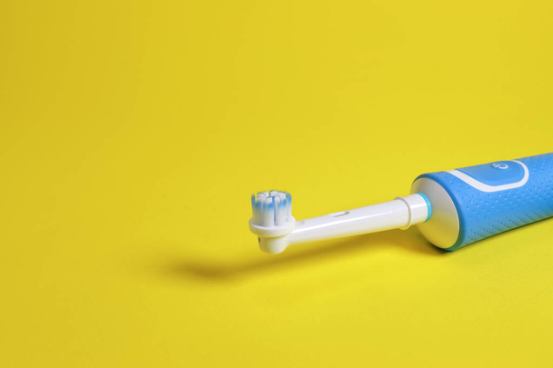 Электрическая зубная щетка на желтом фоне. пространство для копирования текста - Фото, изображение