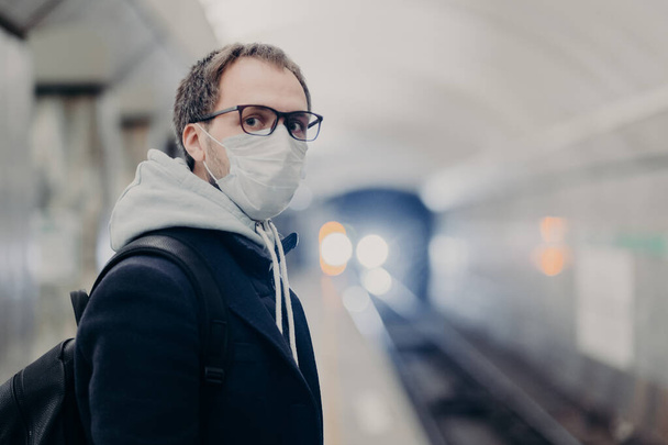 Coronaviruscrisis. Man volgt quarantaine regels draagt beschermende medische masker, reizen in het openbaar vervoer zorgt voor de gezondheid tijdens epidemie of pandemie. Gevaar voor het oplopen van virussen in het stadsvervoer - Foto, afbeelding