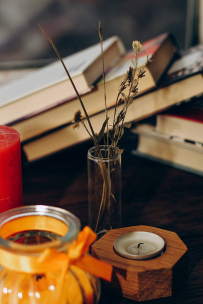 Still life with skins, Orange aroma candle in a figured candlestick with a bow and books on the background. - Foto, Imagen