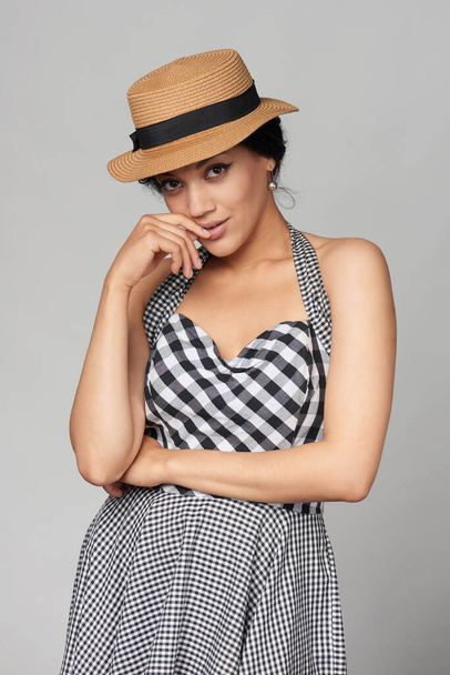 Mixed race african american - caucasian woman in chequered summer dress and canotier straw hat looking at camera, studio portrait - Foto, immagini