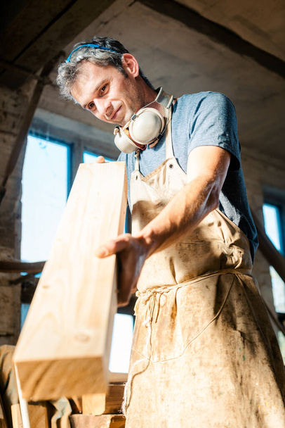 Hombre carpintero en su taller eligiendo madera para el próximo proyecto
 - Foto, imagen