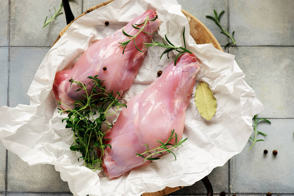Raw rabbit legs with fresh herbs.style hugge.selective focus - Foto, afbeelding